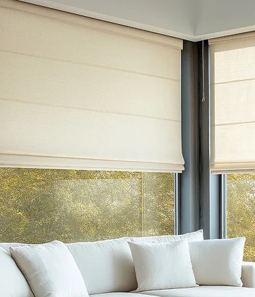 Cream Roman shades above a white sofa in a bright living room