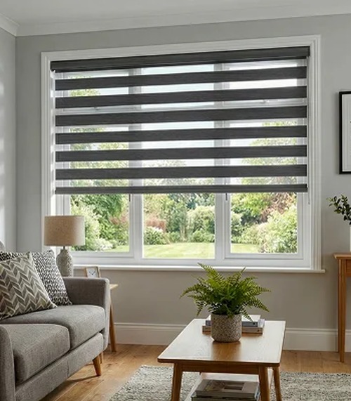 Gray zebra shades on a living room window overlooking a garden